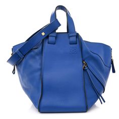 This is an authentic LOEWE Calfskin Medium Hammock Shoulder Bag in Electric Blue. This elegant handbag is crafted of blue calfskin leather. The bag features front and back zippers to expand the width of the bag, an optional shoulder strap, side top handles and gold hardware. The open top leads to a spacious black fabric interior with patch pockets on either side. Blue Textured Calf Leather Bag, Luxury Blue Calf Leather Bag, Blue Calf Leather Shoulder Bag With Detachable Strap, Blue Calf Leather Bag With Detachable Strap, Modern Blue Leather Satchel, Blue Textured Leather Tote Shoulder Bag, Blue Leather Top Handle Satchel, Blue Textured Leather Tote Bag, Blue Leather Tote Satchel