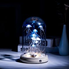 an illuminated jellyfish in a glass dome on a table