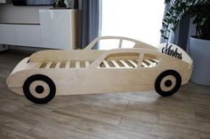 a child's wooden car bed sitting on the floor