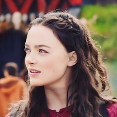 a close up of a person with long hair wearing a red shirt and braids