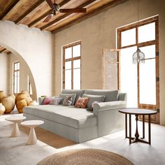 a living room filled with lots of furniture next to large windows and vases on the floor