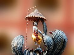 there is a figurine with an umbrella on top of two snakes