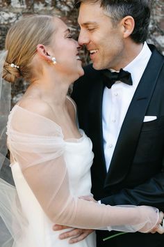 a man in a tuxedo and a woman in a wedding dress smile at each other