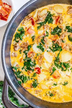 an omelet with meat, cheese and spinach in a pan next to other dishes