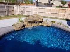 a pool with rocks and water features a waterfall