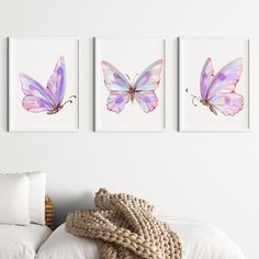 three butterfly paintings hanging on the wall above a bed