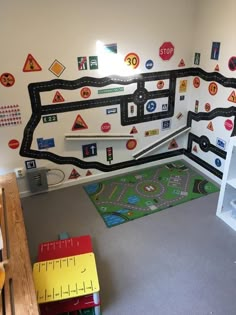 a child's playroom with cars and traffic signs on the wall, rugs and toys