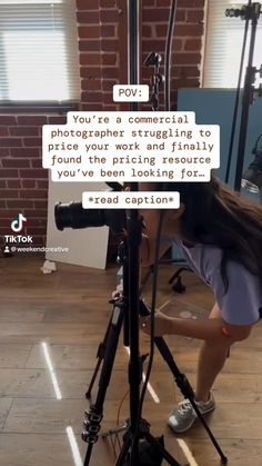 a woman leaning over a tripod with a camera in front of her and texting on it