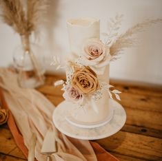 a wedding cake with flowers and feathers on the top is ready to be cut into pieces