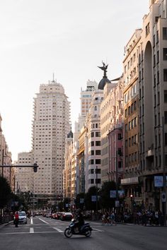 a city street filled with lots of tall buildings and people riding bikes on the sidewalk