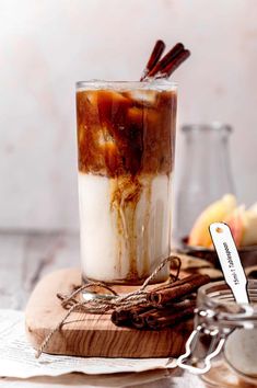 an iced drink with cinnamon sticks in it sitting on a wooden board next to other items