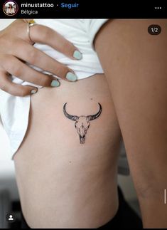 a woman's stomach with a small tattoo of a bull skull on the side