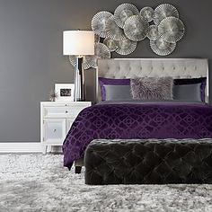 a bed with purple sheets and pillows in a bedroom