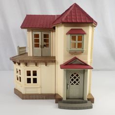 a toy house with a red roof and two windows on the top floor is shown in front of a white background