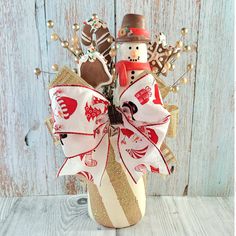 a snowman in a mason jar with candy and candies on the top, sitting against a wooden wall