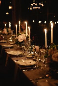 a long table is set with candles and flowers for an elegant dinner or party in the dark