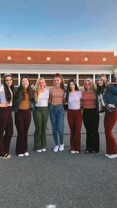 a group of women standing next to each other in front of a building