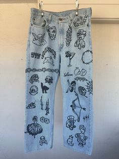 a pair of jeans with drawings on them hanging from a clothes line