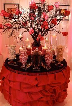 a table topped with red flowers and candles