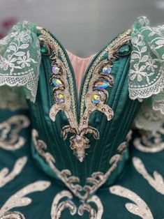 the back of a green dress with white lace on it