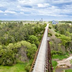 an aerial view of a train going over a bridge in the middle of some trees