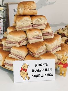 a pile of sandwiches sitting on top of a table next to a winnie the pooh sign