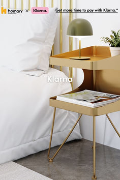 a nightstand with a magazine on it next to a bed