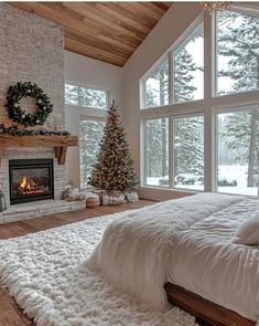 a bedroom with a fireplace, bed and christmas tree in front of the large windows