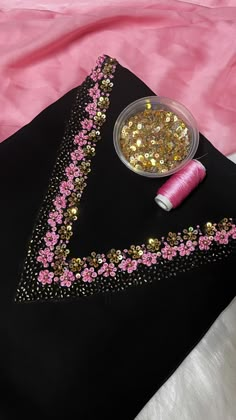 a black bag with pink and gold sequins next to a spool of thread