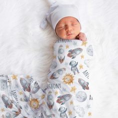 a baby is sleeping on a white blanket with an astronaut themed cover over it's head