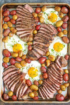 an assortment of meats and eggs on a platter with tomatoes, olives