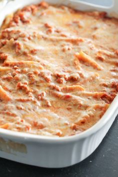 a casserole dish with meat and cheese in it sitting on a black table