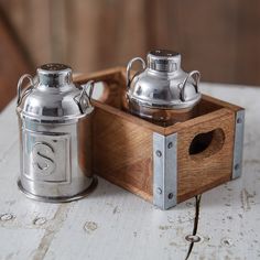 two metal tea kettles sitting on top of a wooden box