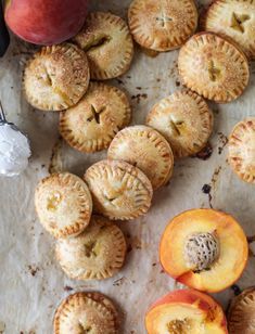 several peach pies on a piece of parchment paper next to some sliced peaches