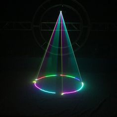 a lit up cone in the middle of a dark room with lights on it and a circular