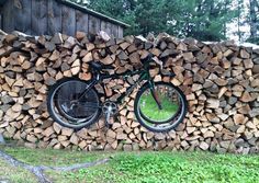 a bicycle is parked on top of a pile of firewood