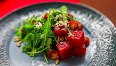 a plate with some food on it and garnished with nuts, greens and feta cheese