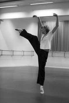 a woman in black pants and white shirt doing a kickbox pose on a dance floor