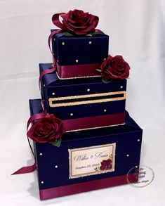 three tiered wedding cake with red roses on the top and purple ribbon around the edges