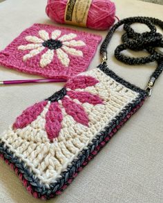 two crocheted purses sitting on top of a table next to a ball of yarn