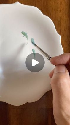 someone is painting a white vase with green paint