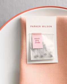 a pink napkin with a label on it sitting on a white plate next to a fork and knife