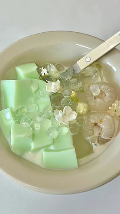 a bowl filled with ice and flowers next to a pair of scissors on top of it