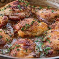 some chicken is cooking in a pan on the stove top with parsley sprinkled around it