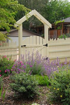 a white picket fence with purple flowers in the foreground