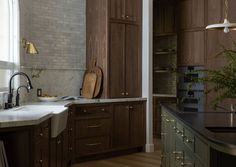 A spacious and stunning kitchen space with curved green tone island and beautiful wood cabinetry.