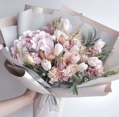 a person holding a bouquet of flowers in their left hand and wrapping it around the other