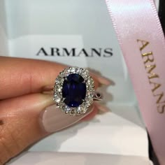 a close up of a person's hand holding a ring with a blue stone