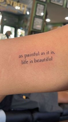 a person with a tattoo on their arm that says as painful as it is, life is beautiful