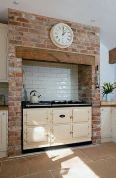 a kitchen with an oven, counter top and clock on the brick wall above it